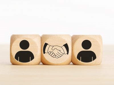 Agreement, partnership or deal concept. People and handshake Icons on wooden blocks. Copy space