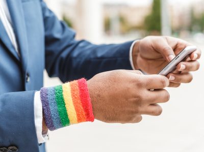 unrecognizable african businessman with LGBT bracelet using smartphone outdoors. Diversity concept.