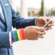 unrecognizable african businessman with LGBT bracelet using smartphone outdoors. Diversity concept.