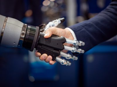 Hand of a businessman shaking hands with a Android robot.