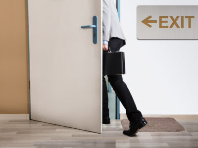 Businessperson,walking,out,with,exit,sign,on,wall